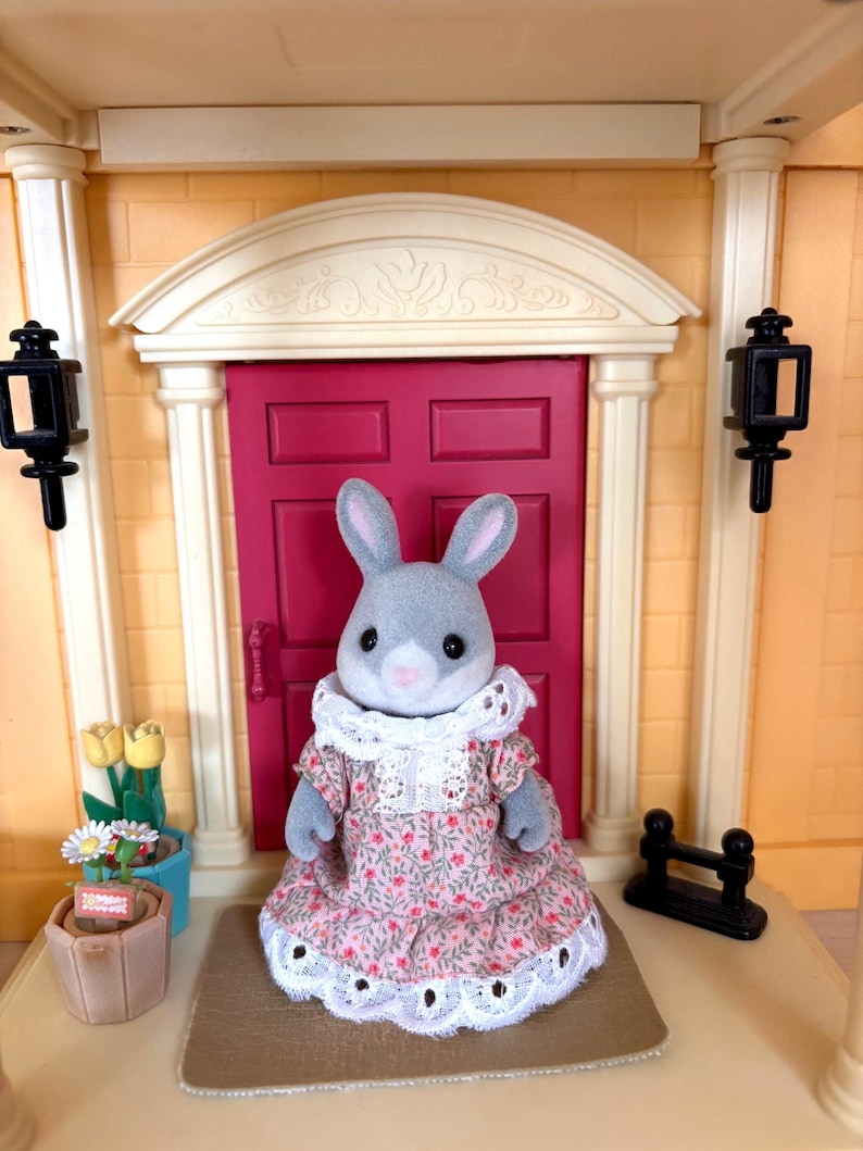 Może przedstawiać: Biały ceramiczny kubek z czarnym uchem i napisem "But First, Coffee" w czarnym kolorze. Kubek jest umieszczony na rozmytym tle.