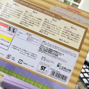May include: A close-up of a box featuring Japanese text and the "Sylvanian Families" logo. The box has a lavender and wood-grain design. The text describes the Lavender Rabbit Family, including character names and birthdays.