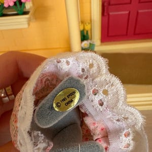 Może przedstawiać: Biały ceramiczny kubek z czarnym uchwytem i napisem "But First, Coffee" czarną, odręczną czcionką. Kubek stoi na białej powierzchni.