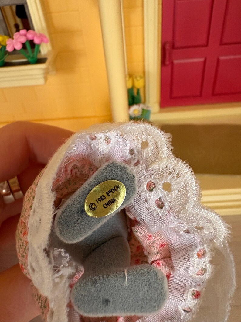 Może przedstawiać: Biały ceramiczny kubek z czarnym uchwytem i napisem "But First, Coffee" czarną, odręczną czcionką. Kubek stoi na białej powierzchni.