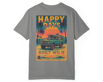 May include: A gray t-shirt with a graphic print of a green vintage off-road vehicle driving on a beach at sunset. The graphic includes the text "Happy Days" and "Built Wild".