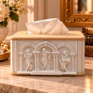 Puede incluir: Una caja para pañuelos rectangular con una tapa beige y una base blanca que presenta tres nichos arqueados. Cada nicho contiene un relieve blanco de una figura humana entre columnas. Un pañuelo blanco sobresale por la ranura superior.