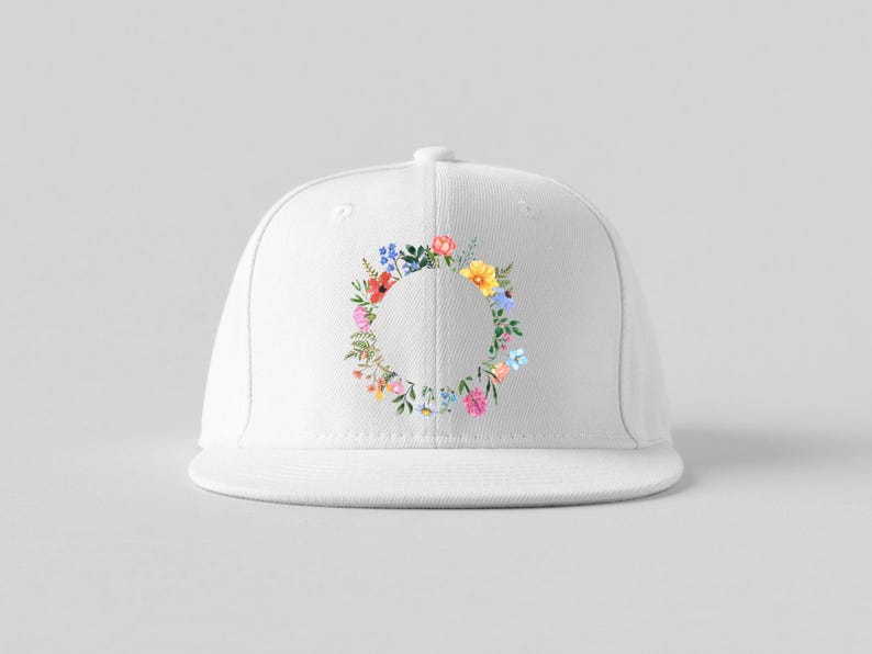 May include: A white baseball cap featuring a colorful floral wreath design. The wreath is composed of various flowers in shades of pink, yellow, blue, and green, arranged in a circular pattern around the cap's front.