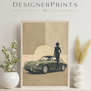 Puede incluir: Una impresión artística enmarcada que presenta un coche deportivo verde vintage y la silueta de una mujer. La impresión tiene un fondo beige y marrón con el texto "CLASSIC DRIVE". Las palabras "DESIGNERPRINTS AU" están en la parte superior.