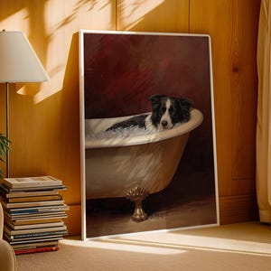 May include: A framed print of a black and white Border Collie dog relaxing in a vintage bathtub filled with bubbles. The artwork has a dark red background and is displayed in a room with a lamp, books, and a beige armchair.