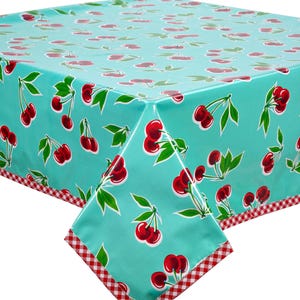 May include: A turquoise tablecloth with a repeating pattern of red cherries and green leaves. The edges are trimmed with a red and white gingham pattern. The tablecloth is made of a shiny, waterproof material.