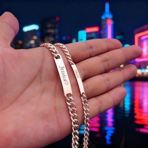Puede incluir: Pulseras de cadena de oro rosa con placas grabadas. Una placa dice "Jessica" con un corazón, la otra dice "David". Las pulseras presentan un diseño de cadena de eslabones, perfectas para regalos personalizados.