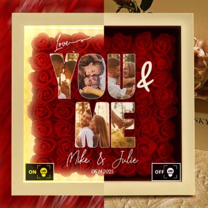 Puede incluir: Un marco blanco con rosas rojas y fotos que deletrean "YOU & ME". El marco tiene una luz LED cálida. Los nombres "Mike & Julie" y la fecha "06.14.2025" también son visibles.