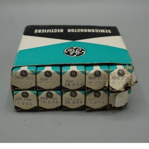 May include: A rectangular cardboard box containing ten smaller individual boxes of GE semiconductor rectifiers. The packaging is white, black, and teal with the GE logo printed on each unit. Each small box is labeled with HDW INCL and IN 256.