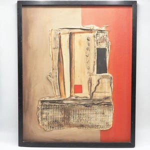 May include: Abstract mixed media artwork in a black frame. The artwork features a textured, layered composition with beige, red, and black elements. A small red square is visible. The artwork has a vertical orientation.