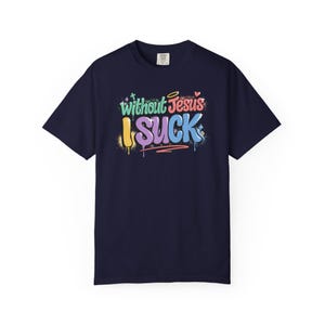 A navy blue t-shirt with the colorful graffiti-style text "Without Jesus I Suck" is laid flat against a white background.