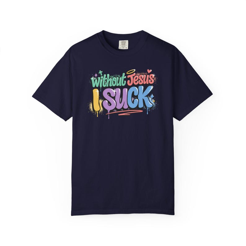 A navy blue t-shirt with the colorful graffiti-style text "Without Jesus I Suck" is laid flat against a white background.