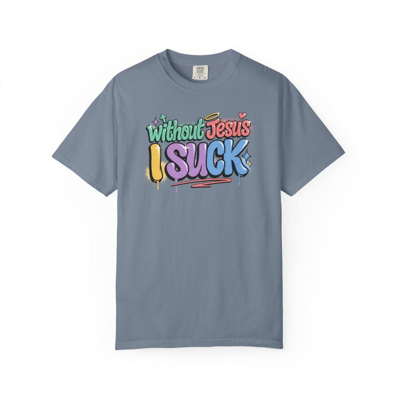 A light blue t-shirt with the colorful graffiti-style text "Without Jesus I Suck" is laid flat against a white background.