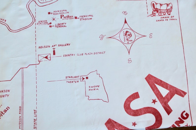 May include: A red and white map of a city with the words "Puritan Maid" and "Origin of Santa Fe Trail".