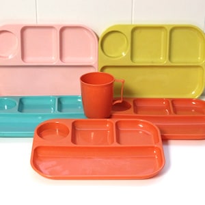 May include: Four divided plastic trays in pink, yellow, blue, and orange, with a single orange plastic cup with a handle.