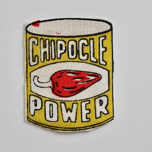May include: A rectangular patch with a yellow background and black border. The patch features the words "CHIPOCLE POWER" in black block letters. A red chili pepper is in the center. The patch is made of fabric.