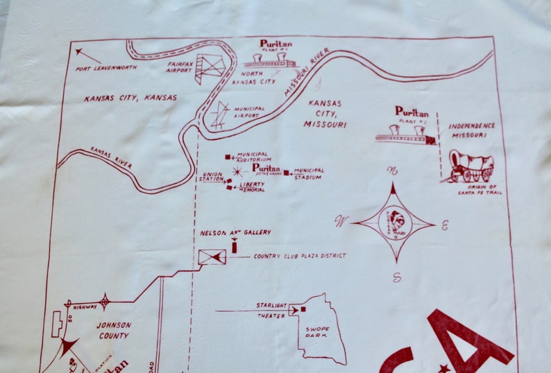 May include: A vintage map of Kansas City, Missouri, with red text and lines on a white background. The map shows the location of various landmarks, including the Municipal Auditorium, Liberty Memorial, Municipal Stadium, Nelson Art Gallery, Country Club Plaza District, Starlight Theater, Swope Park, and the origin of the Santa Fe Trail. The map also includes the text "Puritan Plant No. 1" and "Puritan Plant No. 2".