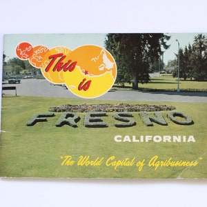 May include: A vintage postcard featuring a green lawn with the words "This is Fresno, California" in large letters. The postcard also features a stylized map of California with a red star marking Fresno.