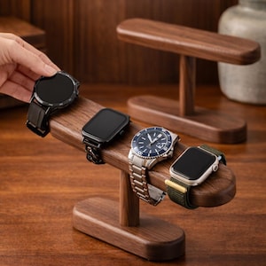 May include: A wooden watch stand displaying four different smartwatches and a wristwatch. The stand is made of dark wood and has a curved design. The watches have black, silver, and blue faces with various band styles.