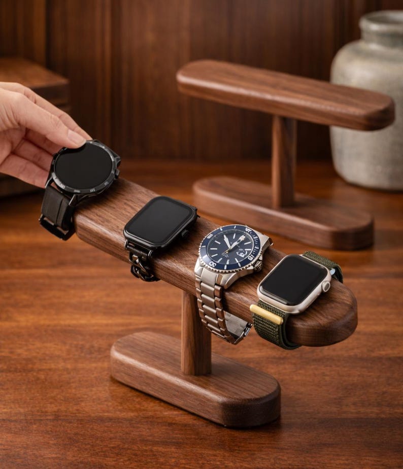 May include: A wooden watch stand displaying four different smartwatches and a wristwatch. The stand is made of dark wood and has a curved design. The watches have black, silver, and blue faces with various band styles.