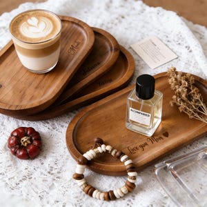 Könnte beinhalten: Holzserviertabletts mit eingravierten Namen und einem herzförmigen Design. Ein Glas Latte mit Herzdesign, eine Parfümflasche, ein Armband und ein dekorativer Kürbis sind ebenfalls vorhanden.