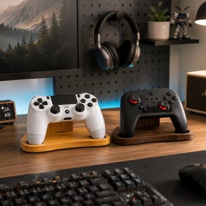 May include: Two wooden controller stands holding gaming controllers. One stand is light-colored wood holding a white controller with black buttons, and the other is dark-colored wood holding a black controller with red accents on the analog sticks.