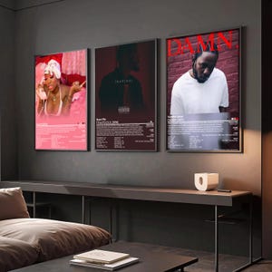 May include: Three framed music posters hang on a dark gray wall. The posters feature album art for "Over" by Summer Walker, "TRAPSOUL" by Bryson Tiller, and "DAMN." by Kendrick Lamar. Each poster has a black frame and includes album details.