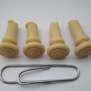 Peut inclure: Quatre chevilles de chevalet de guitare en plastique de couleur ivoire avec un motif circulaire sur le dessus.