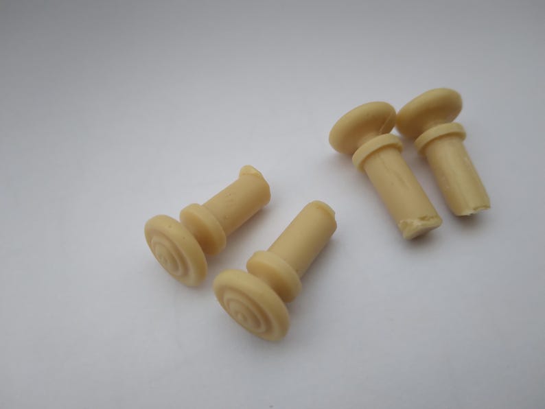 Peut inclure: Cinq embouts de pieds de meubles en plastique beige avec un dessus rond et une base cylindrique.