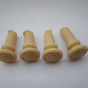 Peut inclure: Quatre bouchons en caoutchouc beige avec un motif stri&eacute;. Les bouchons sont cylindriques avec un sommet arrondi.