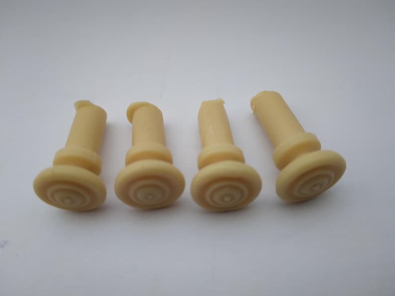 Peut inclure: Quatre bouchons en caoutchouc beige avec un motif stri&eacute;. Les bouchons sont cylindriques avec un sommet arrondi.