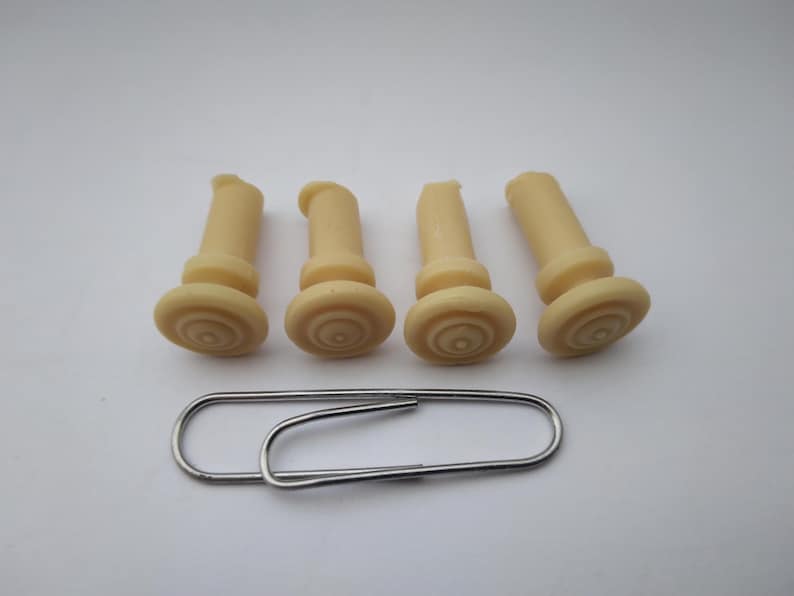 Peut inclure: Quatre chevilles de chevalet de guitare en plastique de couleur ivoire avec un motif circulaire sur le dessus.