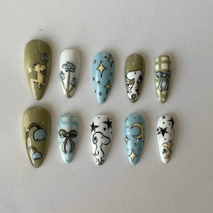 Uñas postizas con estrellas de Snoopy y Woodstock, diseño de uñas con dibujos animados en tonos pastel azul verdoso, puntas de cielo nocturno celestial pintadas a mano