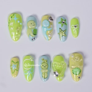 Uñas postizas Smiski verdes, set de uñas con adorables personajes extraterrestres, uñas pastel que brillan en la oscuridad, diseño de uñas kawaii con dibujos animados en menta