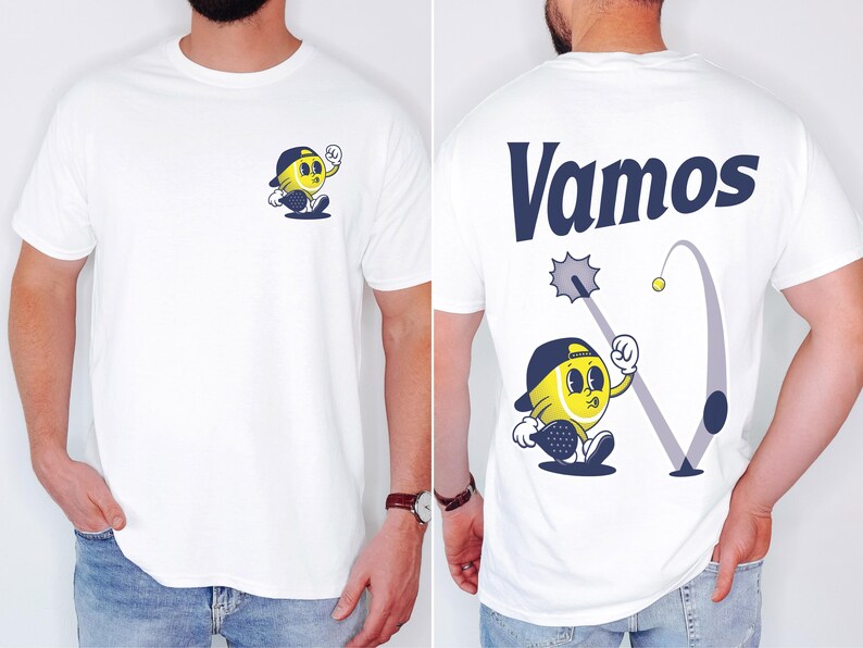 May include: White t-shirt with a cartoon tennis ball character wearing a hat and holding a racket on the front. The back of the shirt has the word "Vamos" in blue lettering and a cartoon tennis ball character swinging a racket.