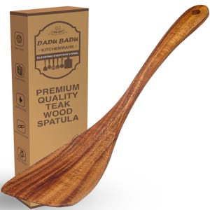 May include: A premium quality teak wood spatula with a long handle and a wide, flat head. The spatula is a warm brown color and has a natural wood grain pattern. The packaging box reads "DADU BADU KITCHENWARE" and "PREMIUM QUALITY TEAK WOOD SPATULA."