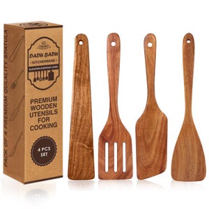 May include: A set of four wooden cooking utensils, including a spatula, slotted spatula, and two other styles. The utensils are made of a light brown wood and are displayed next to a brown cardboard box with text that reads "Premium Wooden Utensils for Cooking."