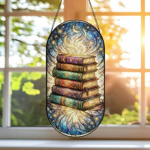 May include: Stained glass window panel featuring a stack of colorful books. The books have ornate covers in shades of purple, green, and gold. The background is a celestial design with stars, a crescent moon, and a glowing light.