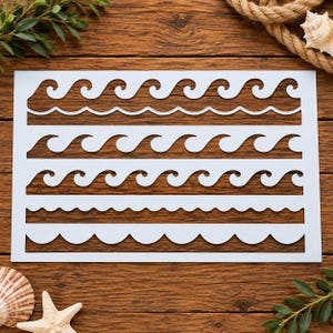 May include: A rectangular white stencil featuring four distinct horizontal rows of cutouts. The top three rows display repeating wave patterns of varying sizes and shapes, while the bottom row consists of a simple, continuous scalloped edge design.