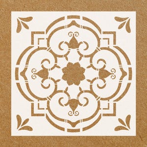 May include: White stencil with a decorative design featuring a repeating pattern of swirls and curves. The design is symmetrical and has a central flower shape.