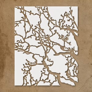 May include: A white paper cut-out featuring a detailed tree branch design. The branches are a warm brown color, creating a contrast against the white background. The artwork is set against a brown backdrop.