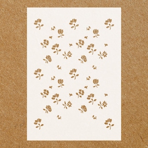 May include: White stencil with a repeating pattern of small brown flowers. The stencil is designed for crafting and decorating projects.