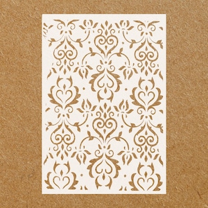 May include: White stencil with a damask pattern. The pattern features repeating swirls and hearts.