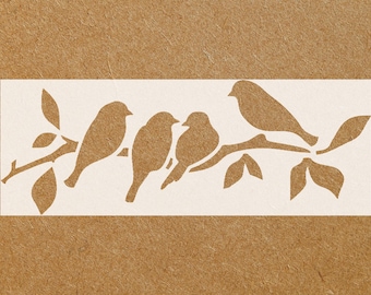 May include: A rectangular stencil featuring four birds perched on a branch with leaves. The birds and branch are a light brown color, set against a white background. The background is a textured, darker brown.