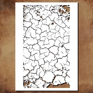 May include: A white rectangular paper with a black cracked earth design. The design features a network of irregular lines and shapes, resembling dried earth. The paper is set against a brown background.