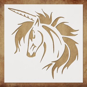 May include: A stencil featuring a stylized unicorn head with a horn and flowing mane. The unicorn design is cut out of a white square, revealing a brown background. The image is suitable for crafts and DIY projects.