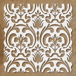May include: White stencil featuring a symmetrical floral and scrollwork pattern. The design is cut out, revealing a brown background. The stencil has a decorative, ornate style, suitable for various craft projects and home decor applications.