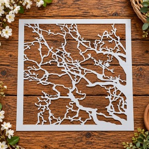 May include: A square white stencil featuring a detailed, intricate cutout design of bare tree branches. The stencil has a solid border frame and displays a complex network of interconnected limbs and twigs, creating a natural, organic pattern.