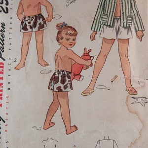 May include: Vintage Simplicity sewing pattern for children's clothing. The pattern is for a pair of shorts with a cow print design and a striped jacket. The pattern is printed on a white background with black text. The text on the pattern reads "Simplicity is America's Fashion" and "Simple to Make".