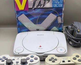 Consola Sony PSOne vintage con accesorios: mandos, adaptador de corriente y multitacto. Sistema de juegos retro.